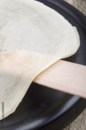 freshly made crepe and a wooden spatula photo