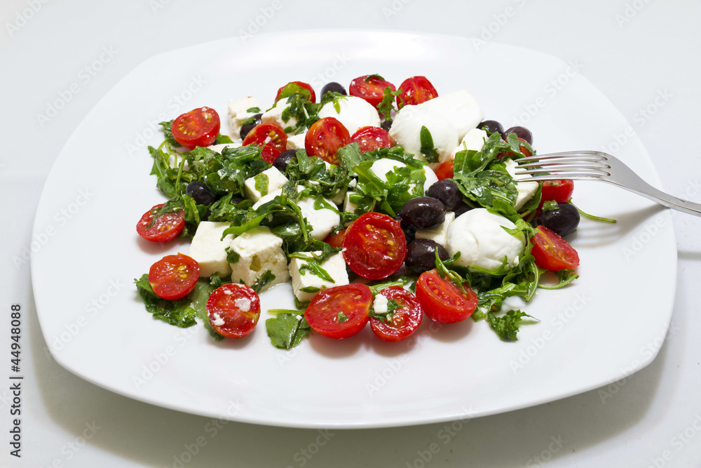 Insalata con rucola, feta, olive nere, mozzarella e pomodorini Insalata con rucola, feta, olive nere, mozzarella e pomodorini
