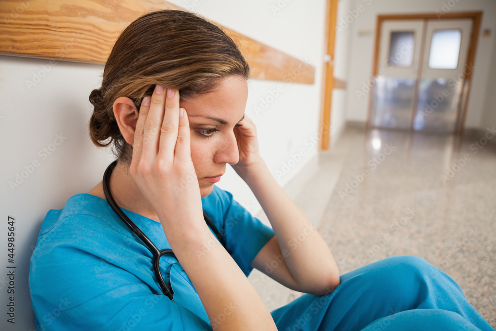 Nurse sitting on the floor hands on head Nurse sitting on the floor hands on head