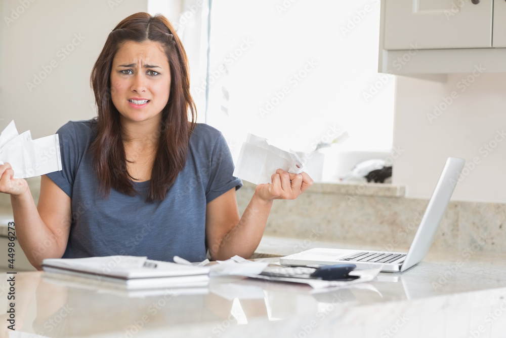 Woman looking troubled while holding bills Woman looking troubled while holding bills