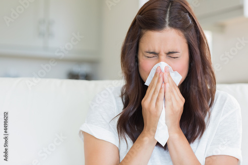 Brunette sneezing in a tissue photo