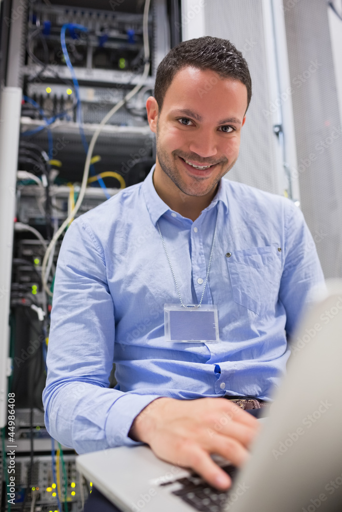 Smiling man working on servers with laptop Smiling man working on servers with laptop