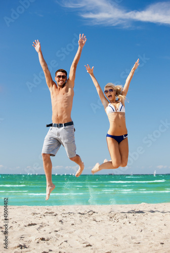 happy couple jumping on the beach