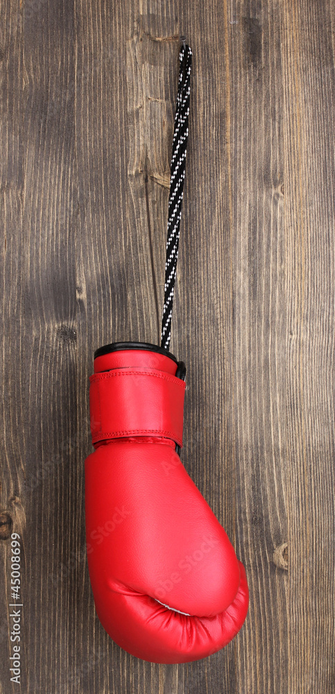 Red boxing glove hanging on wooden background
