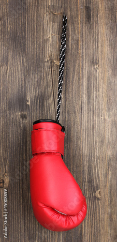 Red boxing glove hanging on wooden background © Africa Studio