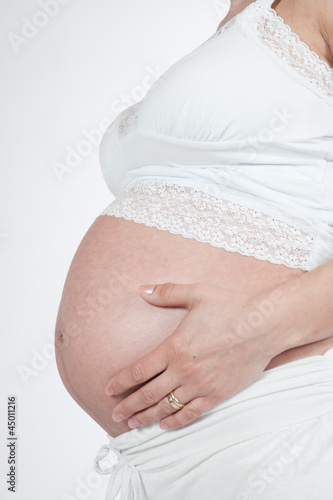 belly of pregnant woman with hands on the breast on white backgr