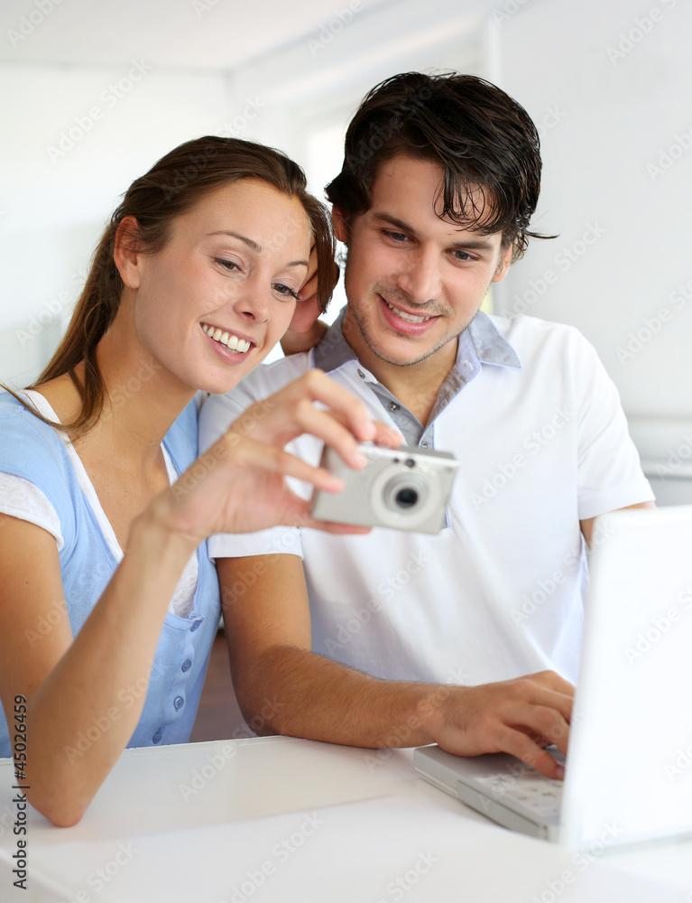 Couple at home uploading photographies on internet Couple at home uploading photographies on internet