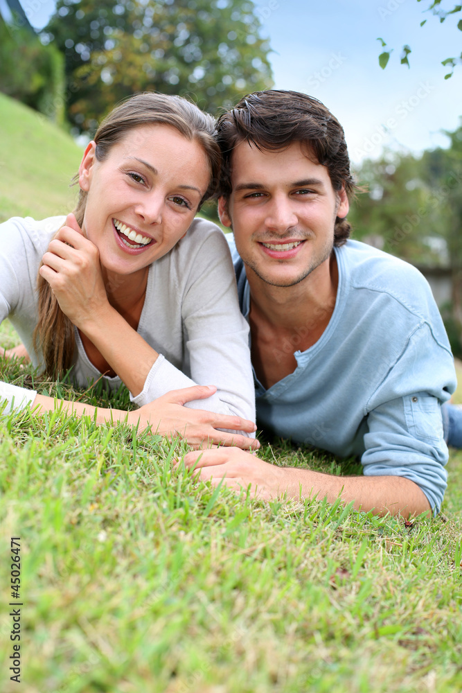 Cheerful couple of lovers laying in garden Cheerful couple of lovers laying in garden