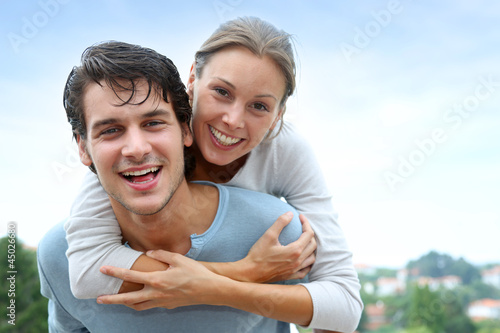 Man giving piggyback ride to girlfriend outside