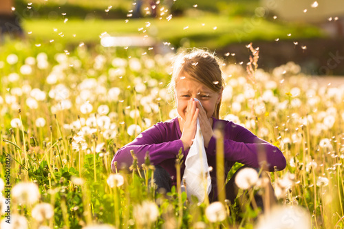 Mädchen auf Wiese mit Pusteblumen und Allergie photo