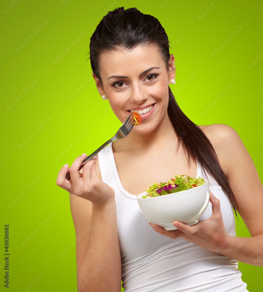 Young woman holding and eating salad Young woman holding and eating salad
