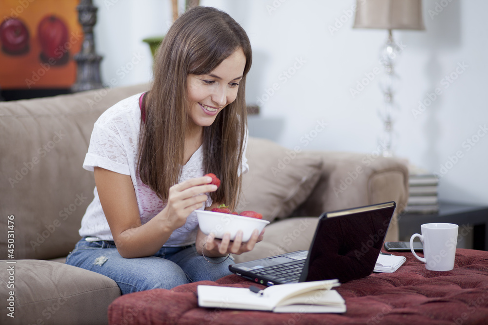 Cute woman eating a snack while working from home Cute woman eating a snack while working from home