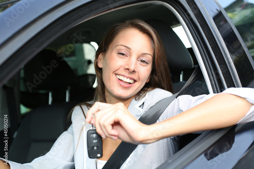 Cheerful girl holding car keys from window