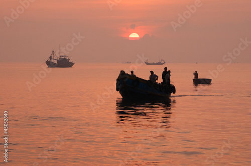 Silhouette of fishing boat return to port after a night of fishi photo