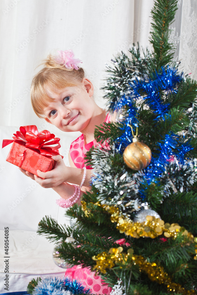 girl with gifts near a New Year tree