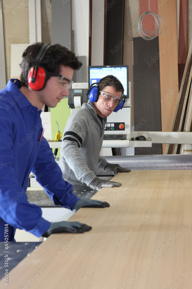 Two workers using factory saw Two workers using factory saw