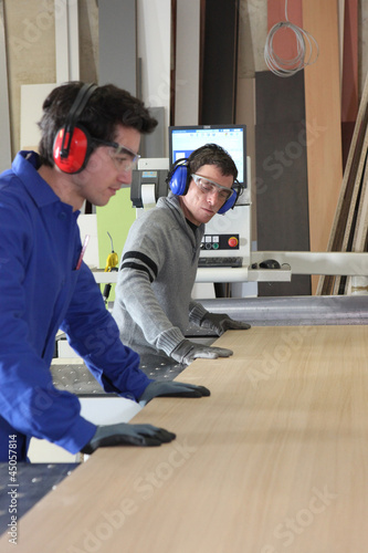 Two workers using factory saw