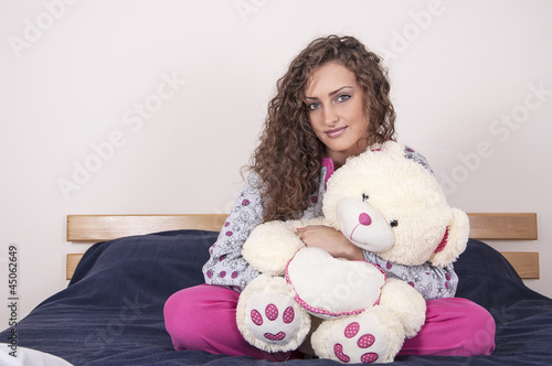 Pretty girl in pajams holding a bear photo