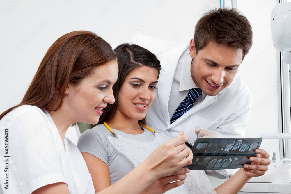 Female Nurse And Dentist Explaining X-Ray Report To Patient Female Nurse And Dentist Explaining X-Ray Report To Patient
