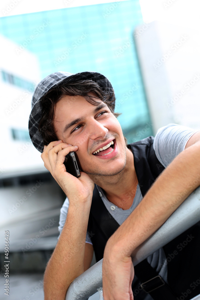 Trendy guy with hat talking on mobile phone