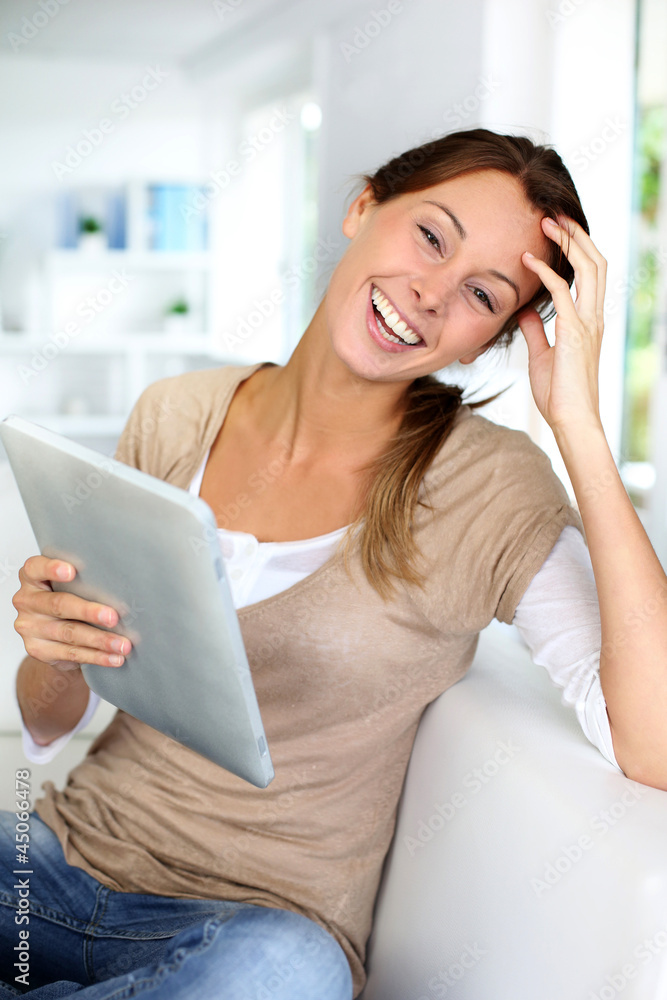Young woman using electronic tablet sitting on sofa Young woman using electronic tablet sitting on sofa