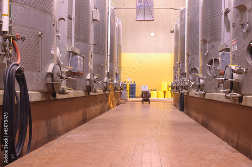 inside a winery cavern with oak barrels and vats, fermentation and storage tanks