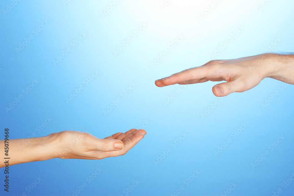 Women's hand goes to the man's hand on blue background