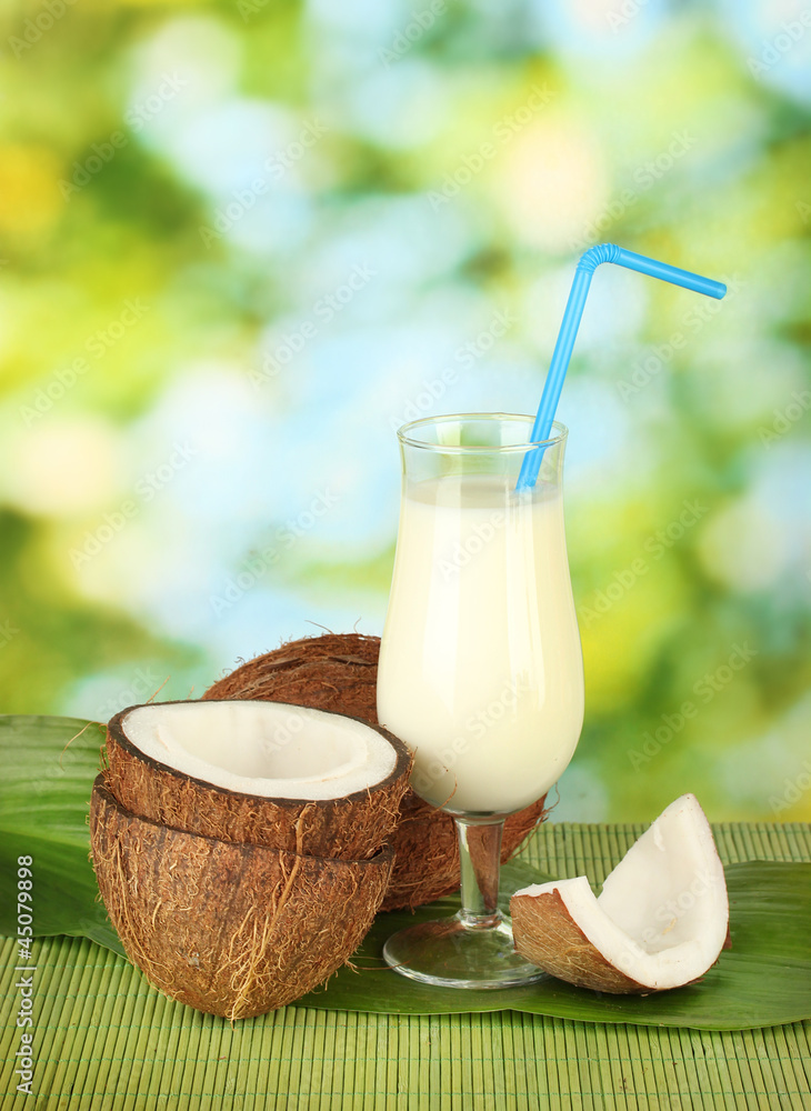 glass of coconut milk and coconuts on green background close-up glass of coconut milk and coconuts on green background close-up