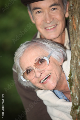 senior couple behind a tree photo