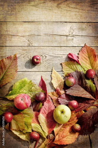 Autumn apples and leaves on wooden table with grunge texture