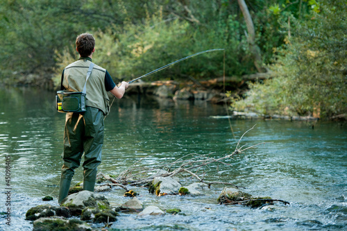 A fisherman fishing on a river photo