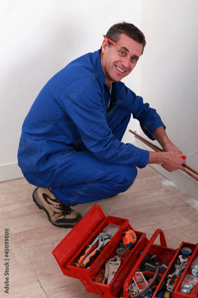 Plumber kneeling by tool box Plumber kneeling by tool box