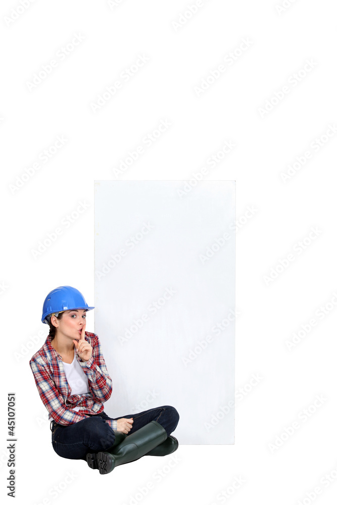 Tradeswoman sitting cross-legged by an empty sign Tradeswoman sitting cross-legged by an empty sign