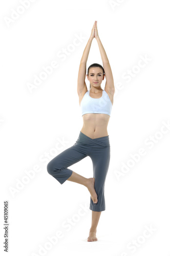 Young woman doing yoga moves or meditating on white