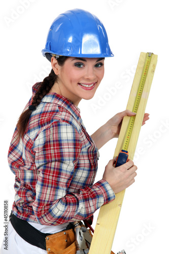 Construction worker measuring a piece of wood