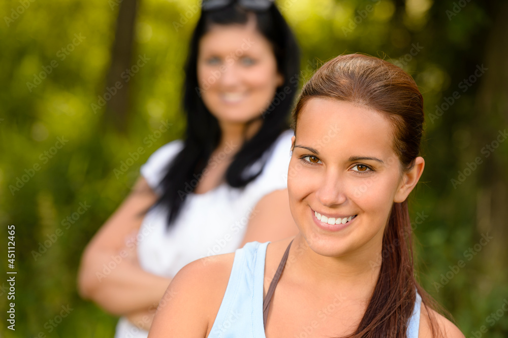Teen girl smiling with mother in background Teen girl smiling with mother in background