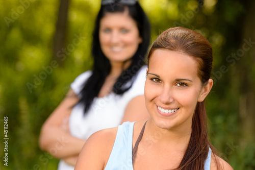 Teen girl smiling with mother in background