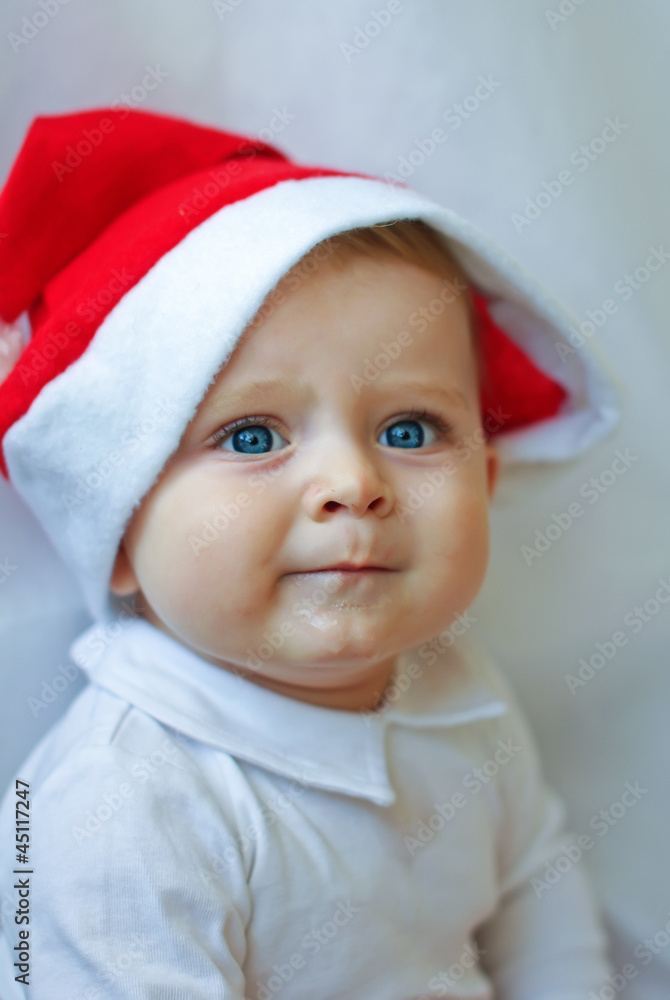 Adorable baby boy in red Christmas cap and ball on white backgro Adorable baby boy in red Christmas cap and ball on white backgro