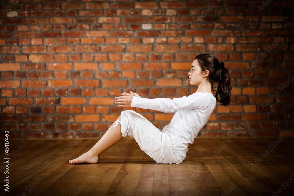Woman exercising yoga against brick wall
