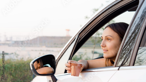 Woman sitting in car with a drink