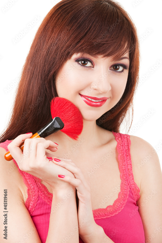 Young woman applying brush for makeup to her face, isolated on w Young woman applying brush for makeup to her face, isolated on w