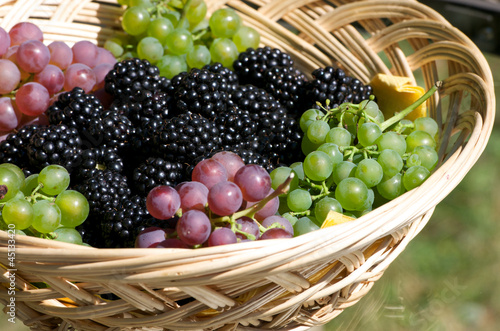 grapes and blackberries in a wooden basket on a glass table