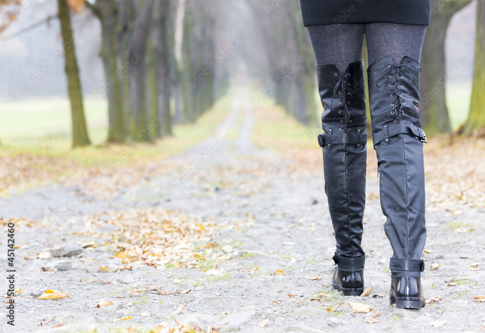 detail of woman wearing black clothes and boots in autumnal alle detail of woman wearing black clothes and boots in autumnal alle