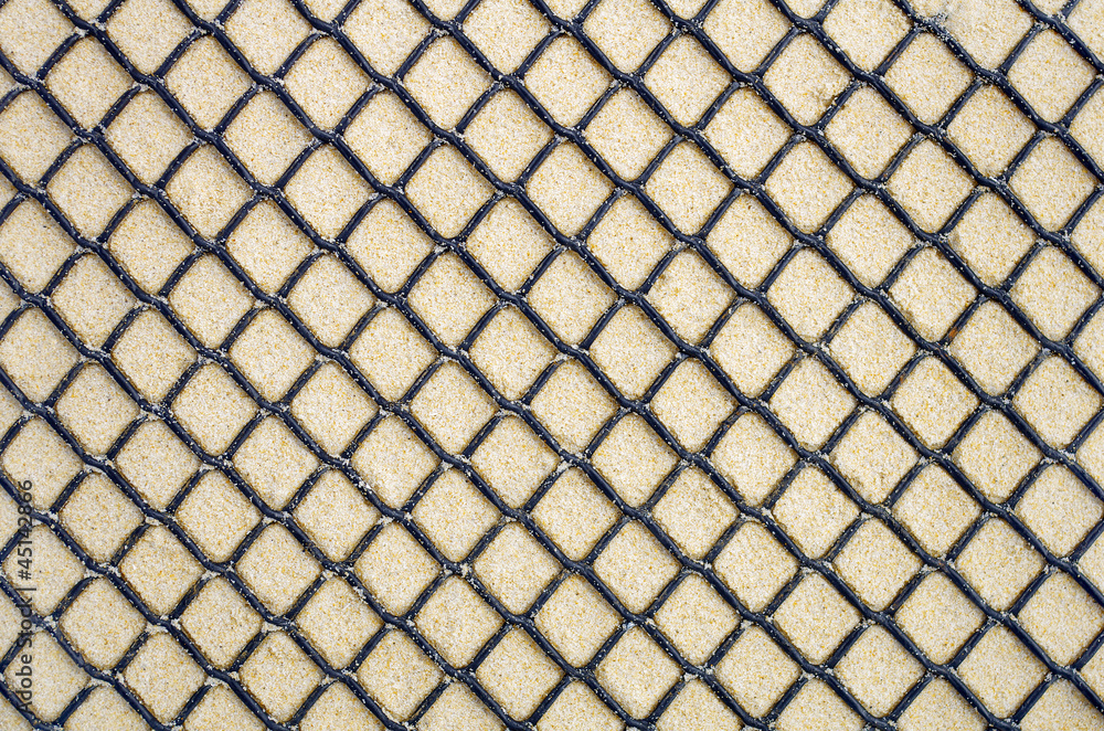 Fototapeta premium Fond de sable derrière une grille plastique