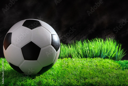 soccer football on gree grass field with black background