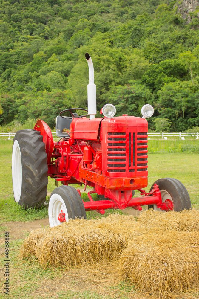 Obraz premium An old red retro tractor in a field
