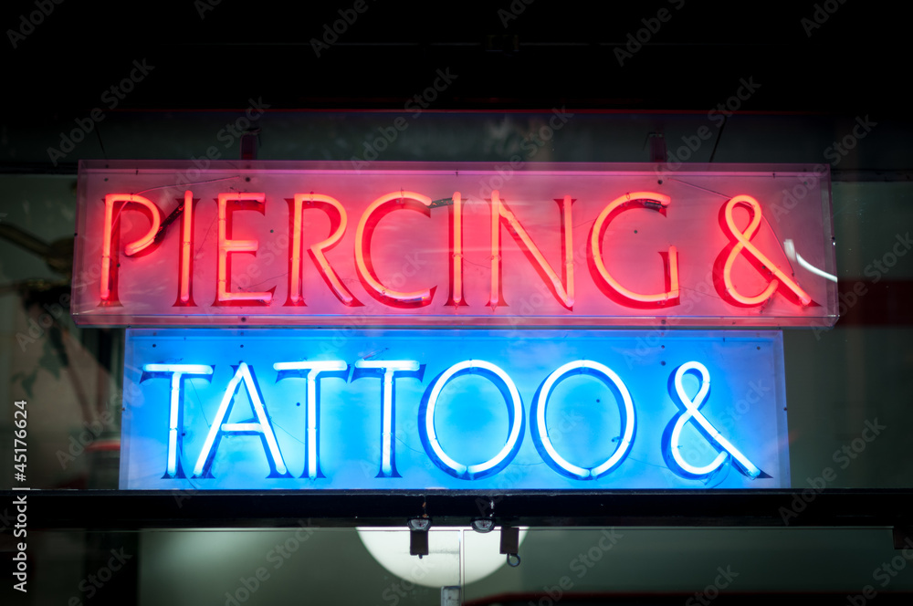 Naklejka premium Neon signboard with Piercing & Tattoo at night.