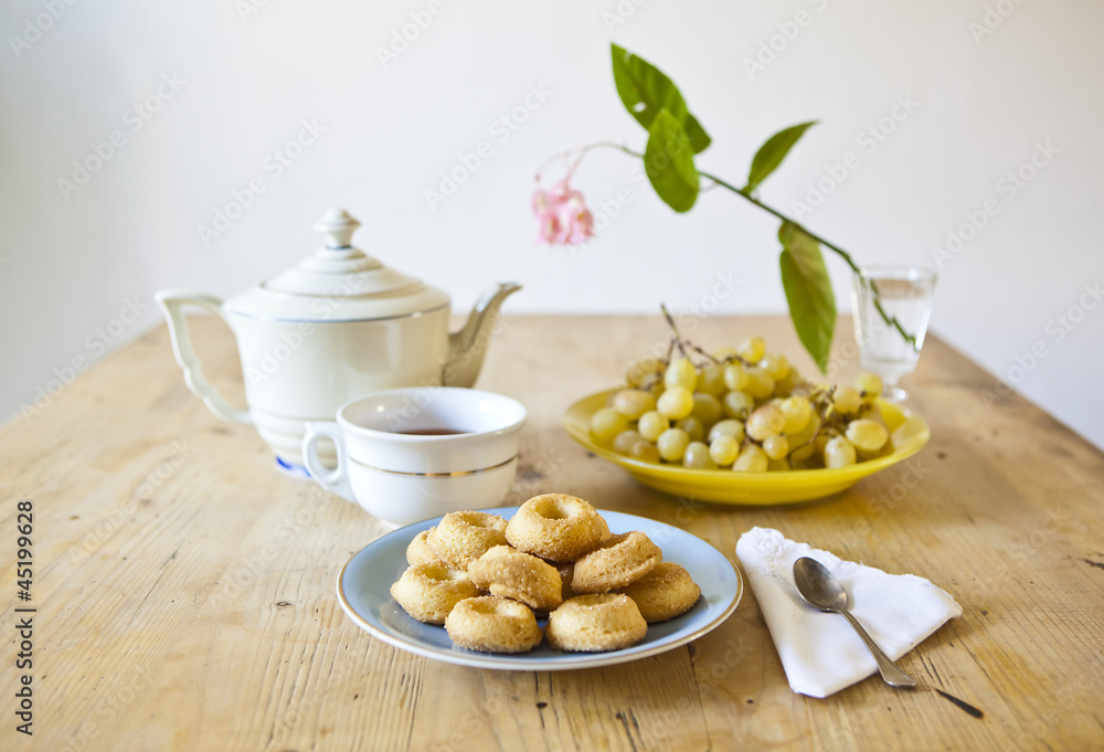 plates of pastries and biscuits and tea pot on wooden table