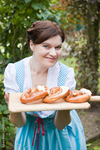 Beautiful woman in dirndl dress holding Oktoberfest  pretzel
