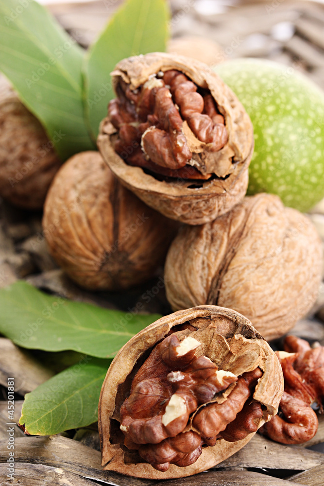 Obraz premium walnuts with green leaves, on wicker background